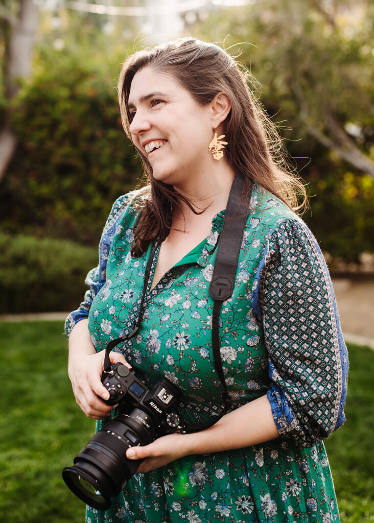 A woman smiling, holding a camera.