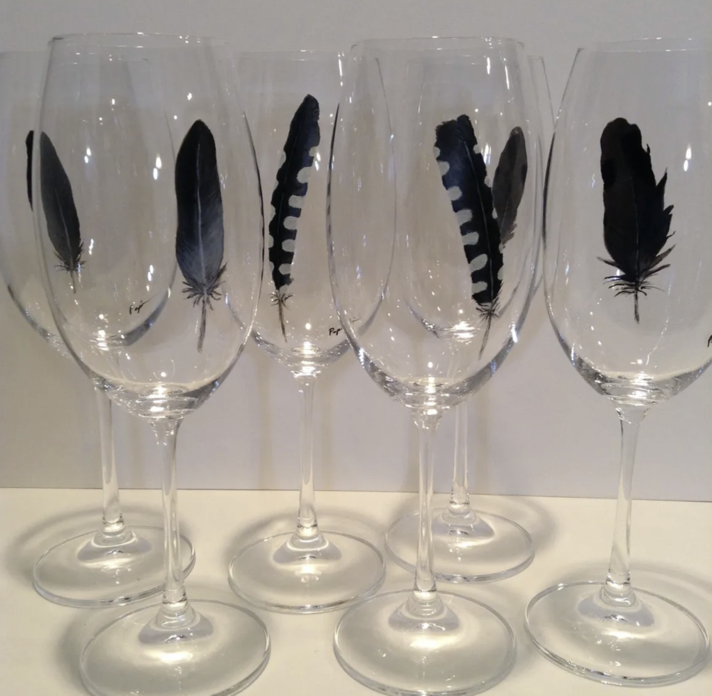 Wine glasses with blue jay feathers painted on them.