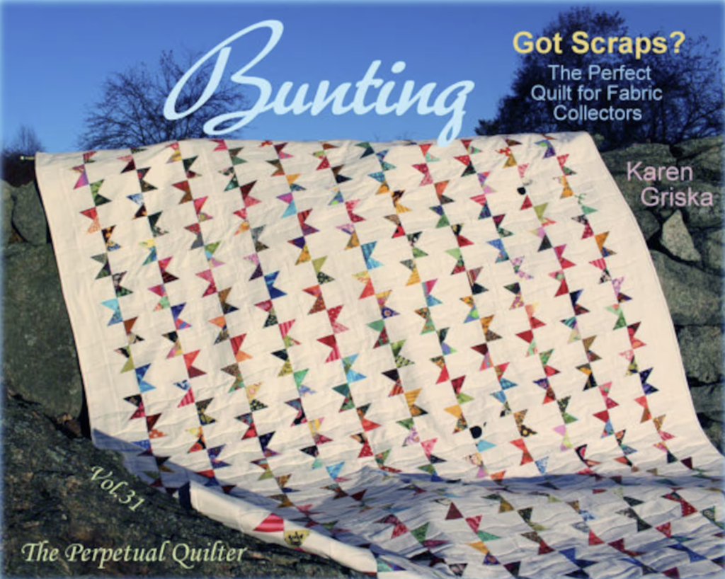 A quilt draped on a rock wall with the words "bunting, got scraps? The perfect quilt for fabric collectors," displayed above it.