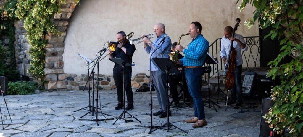 Jazz musicians playing in front of a vine covered wall.