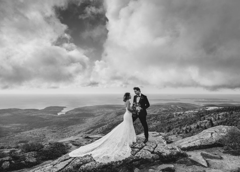 A bride and groom holding hands on top of a scenic landscape.
