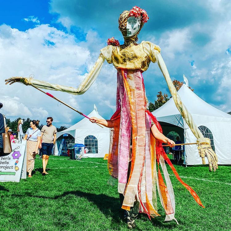 A large puppet walking through a festival outside.